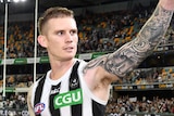 Dayne Beams holds his left hand up and looks out into the crowd after a Collingwood game.