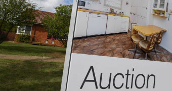 A real estate auction sign in front of a house.