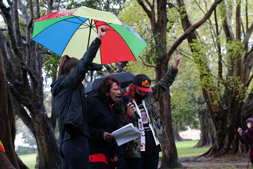A family stands under an umbrella, holding placards with black lives matter slogans.