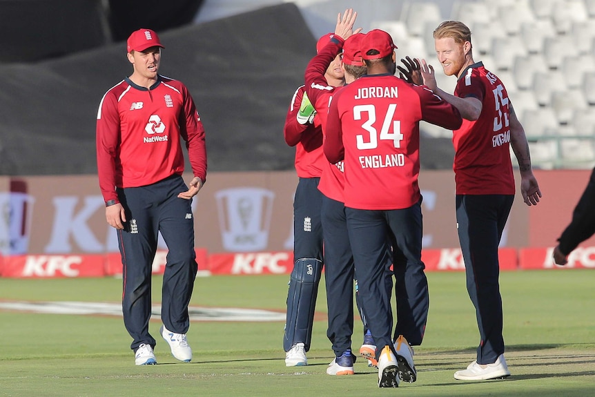 International cricket teammates gather in celebration after taking a wicket in a T20 match.