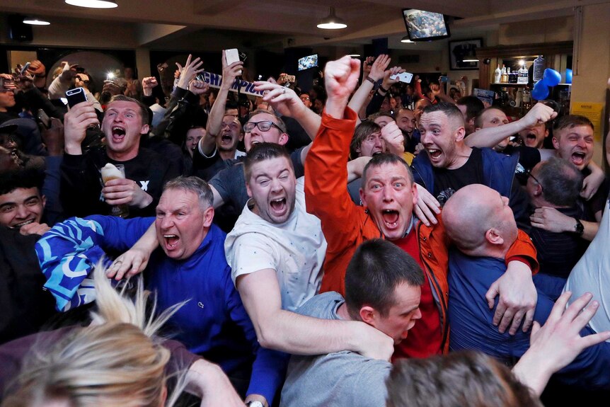 Leicester City fans in a pub leap into the air as they celebrate winning the Premier League.