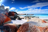 A white sand beach with red rocks.
