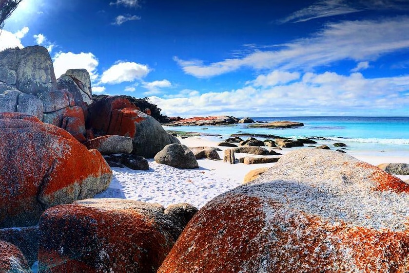 A white sand beach with red rocks.