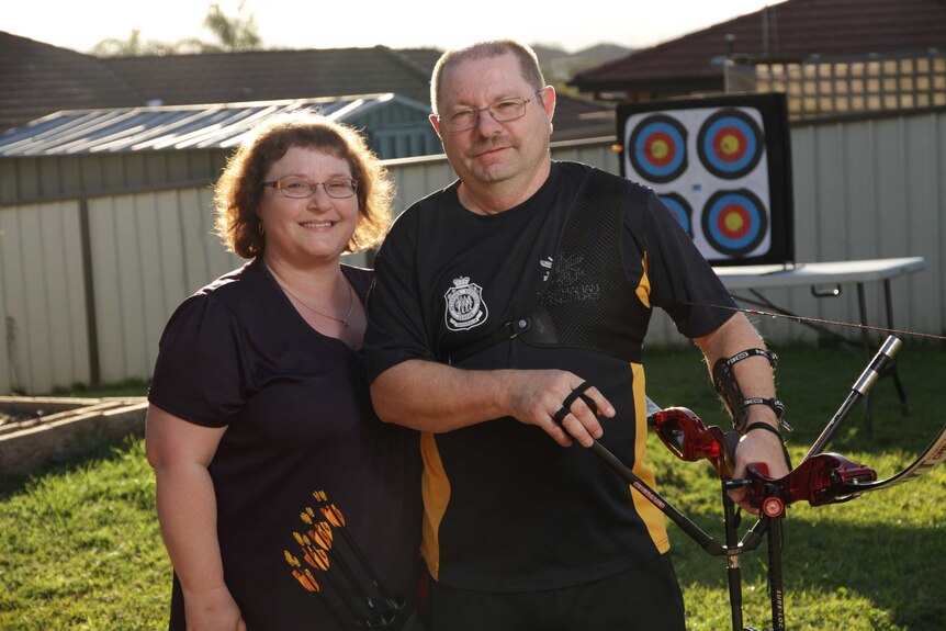 A man and a woman in their backyard practicing archery
