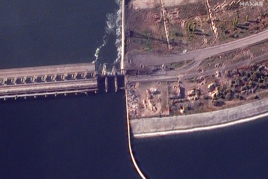 A satellite image shows a damaged section of a dam.