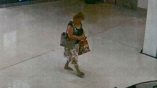 Grainy vision of a woman carrying several bags walking up to an ATM.