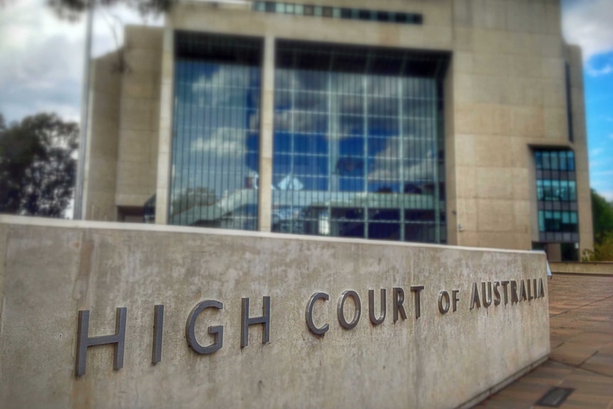 Les mots « Haute Cour d'Australie » sont mis en évidence sur une colonne grise devant le bâtiment de la Haute Cour.