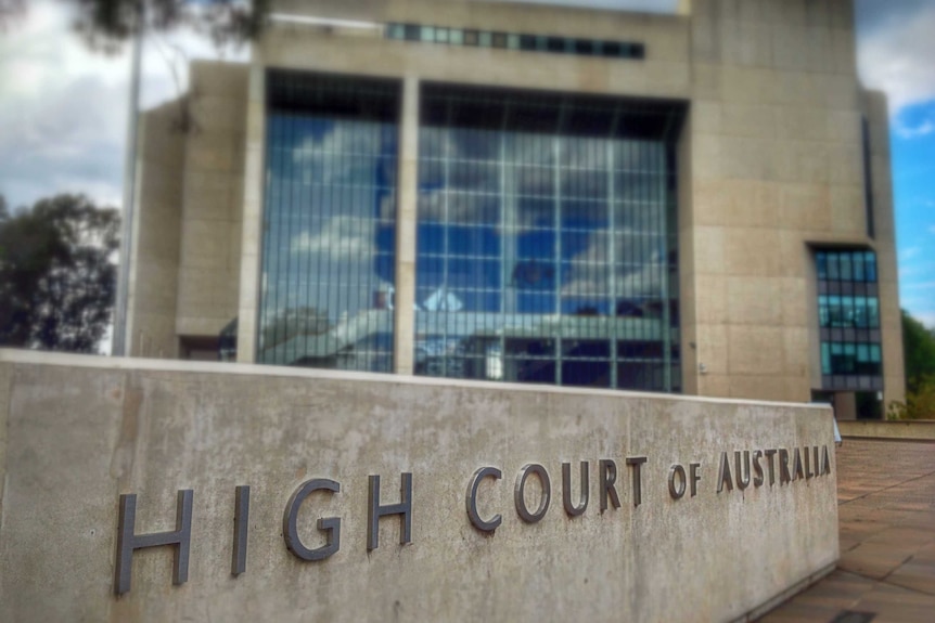 Exterior of a concrete building. High Court of Australia is engraved on a fence. 