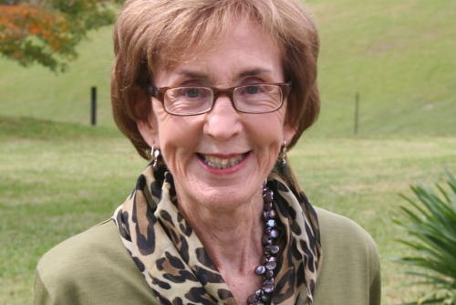 Woman wearing a green top and animal print scarf, smiling.