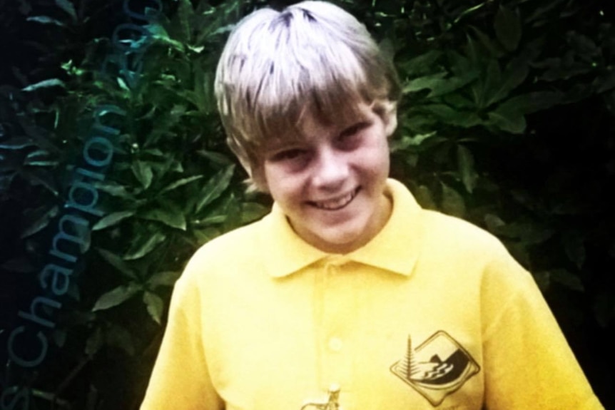 A young James Turner in his yellow school uniform holding running trophy
