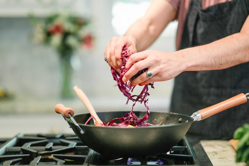 A man cooks dinner for himself in a home kitchen, preparing to enjoy a solo meal.