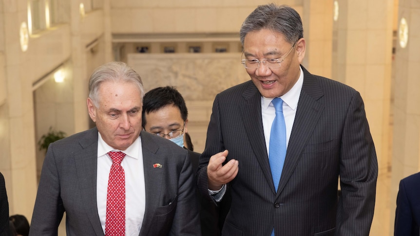 Trade Minister Don Farrell (L) and Chinese counterpart Wang Wentao (R) speaking while going up stairs.