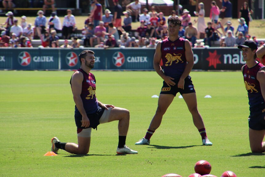 Brisbane Lions players stretch on a football field