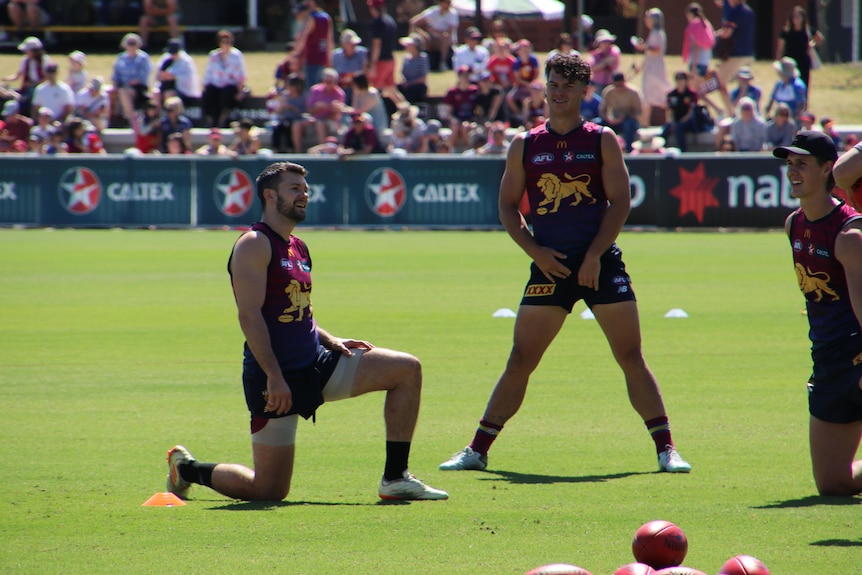 Brisbane Lions players stretch on a football field