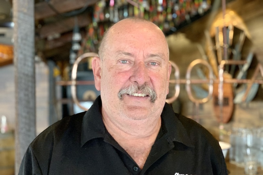 A man wearing a black shirt smiles at the camera