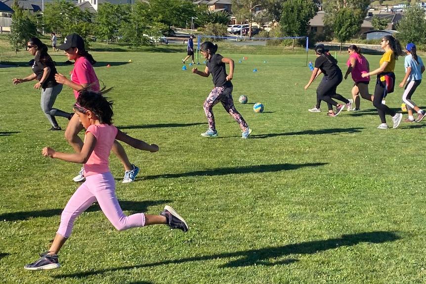 Girls run across a cricket pitch