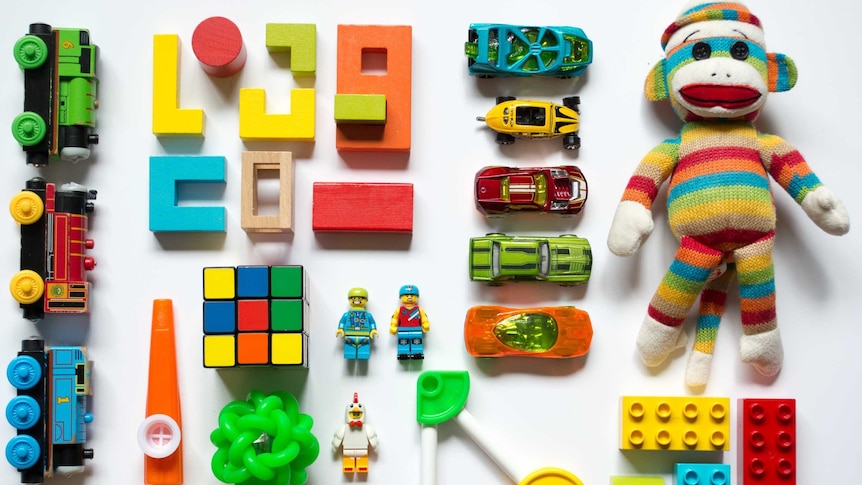 a selection of brightly coloured children's toys lies on a flat surface