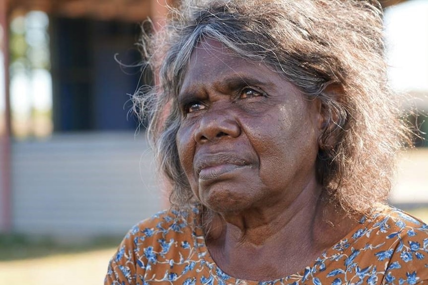 An Aboriginal woman sits outdoors.
