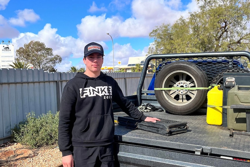 16-year-old boy wearing black hoodie and cap standing next to empty ute tray