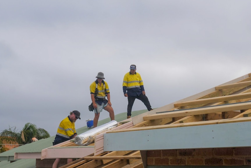 Three builders working on a roof.