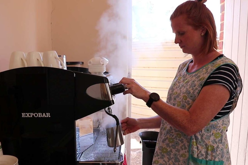 Woman on right using coffee machine letting off steam