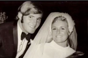 un homme et une femme souriant le jour de leur mariage