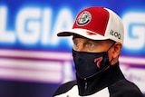 Kimi Raikkonen looks straight out wearing a mask