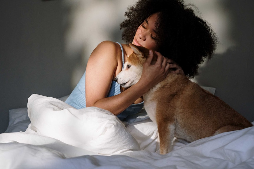Woman hugging dog in bed