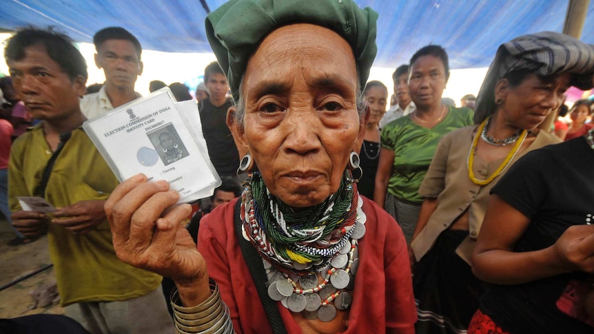 A refugee holds up her voting card as she waits to vote in the 2014  Indian national elections