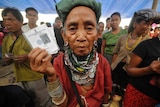 A refugee holds up her voting card as she waits to vote in the 2014  Indian national elections
