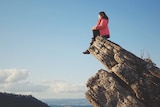 A woman sits on a rock that juts out in Victoria's Cathedral Range State Park.