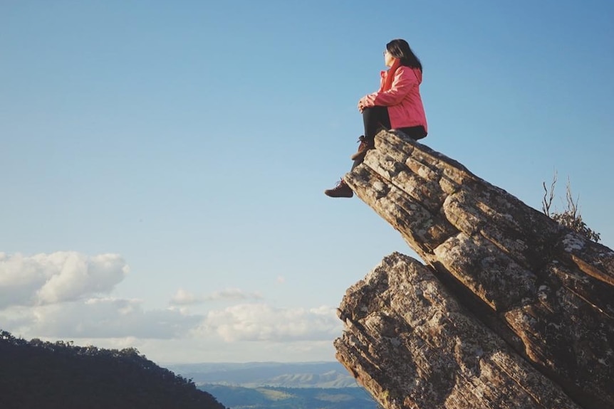 A woman sits on a rock that juts out in Victoria's Cathedral Range State Park.