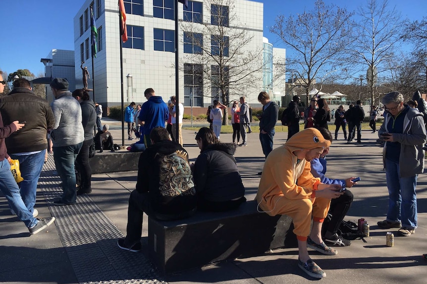 People playing Pokemon Go outside Questacon in Canberra, including one man dressed as a Charmander.