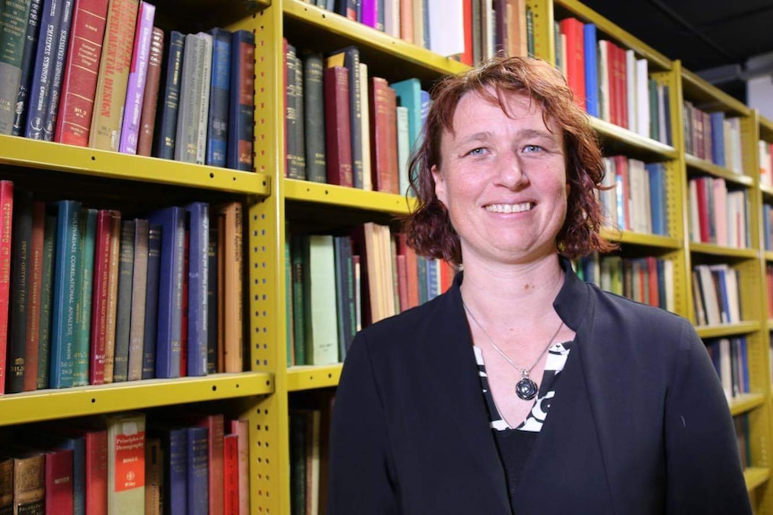 Alison Dellit stands in front of a book shelf.