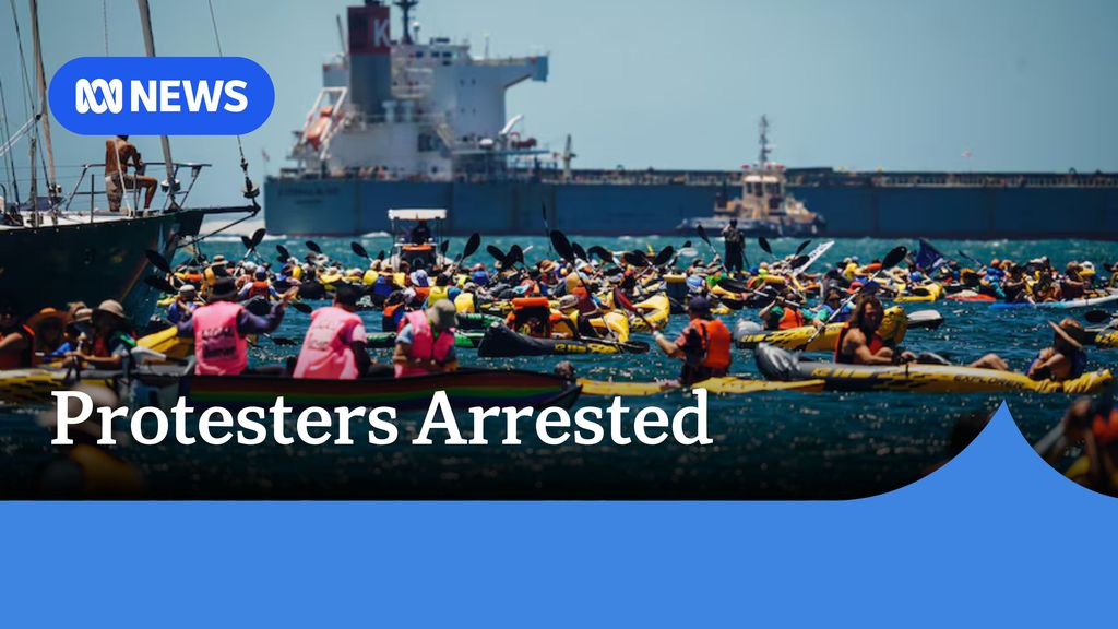 Protesters ARrested: Dozens of people on kayaks and rafts with a large cargo vessel in the background.