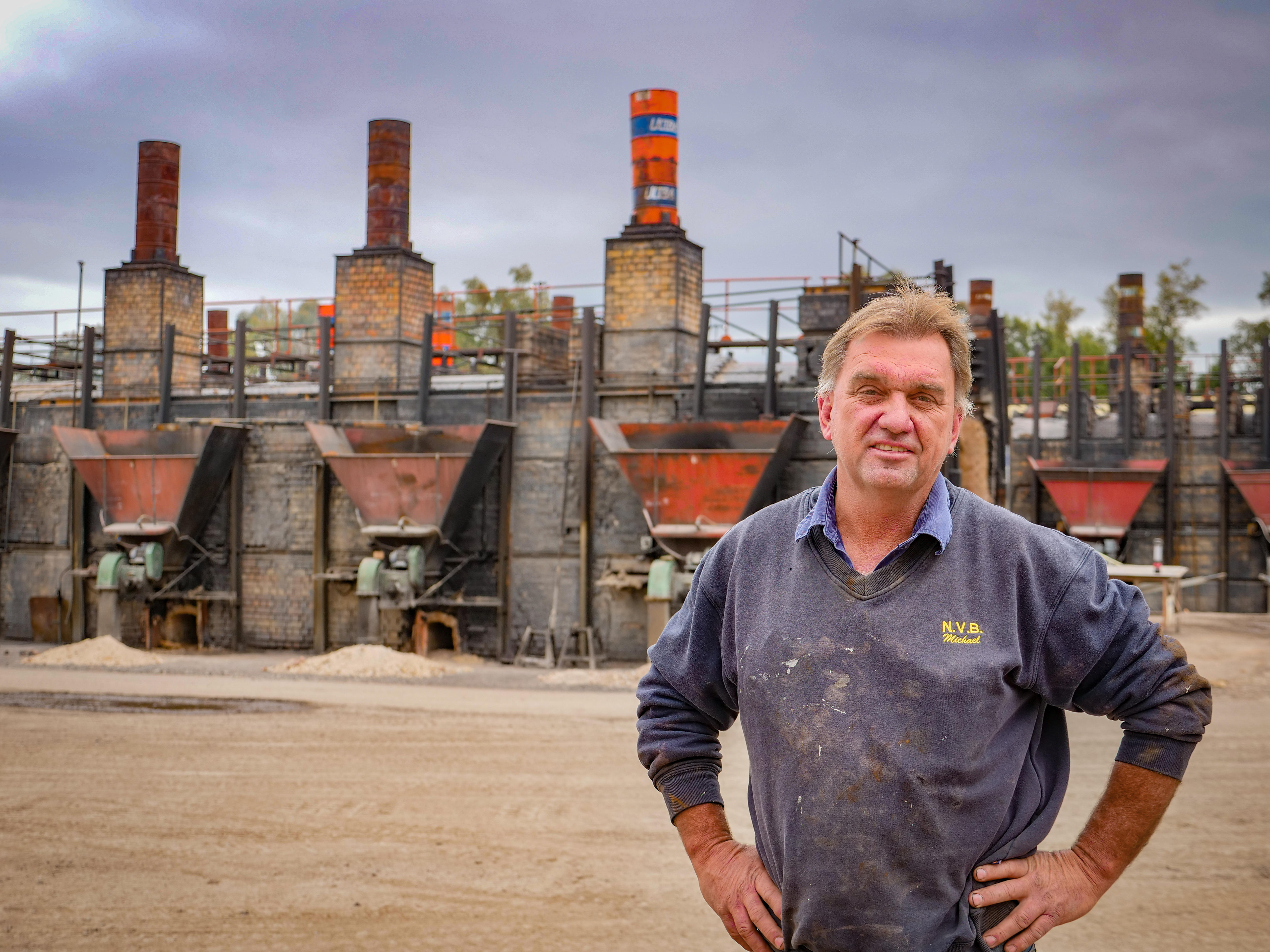 A man stands in front of cola fired brick kilns