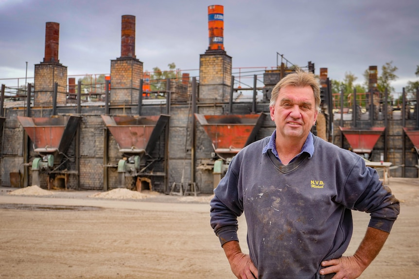 A man stands in front of cola fired brick kilns