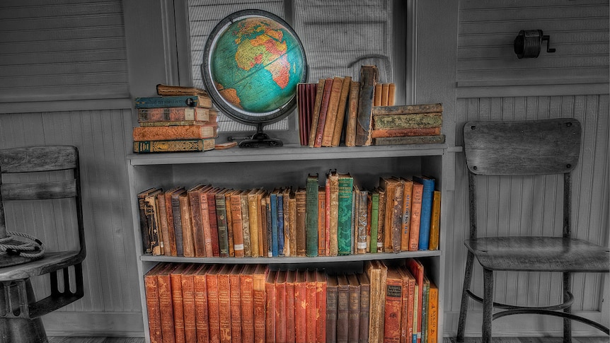 A bookshelf with a globe on top