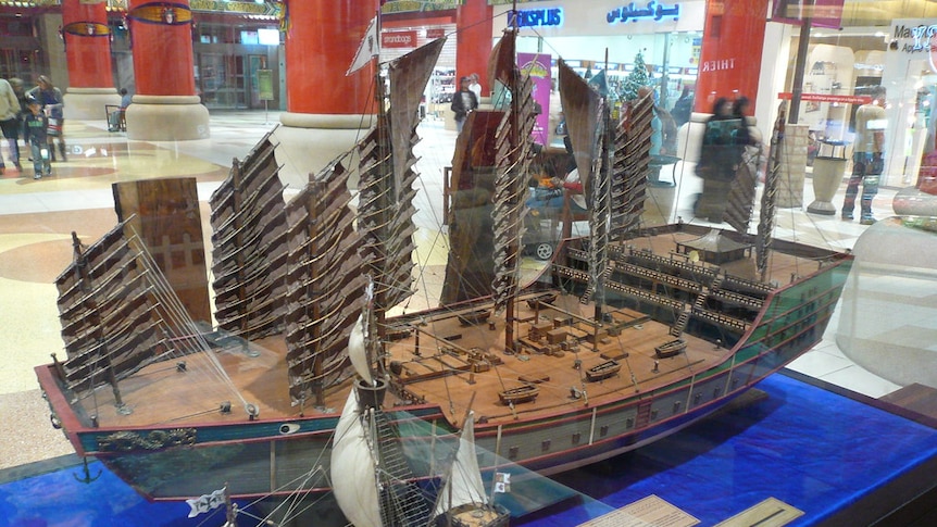 Two model ships are shown to scale - a smaller European one in the foreground and a large junk.