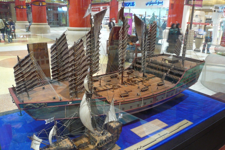 Two model ships are shown to scale - a smaller European one in the foreground and a large junk.