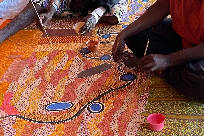 Close up of colourful patterns and artists hands holding brushes