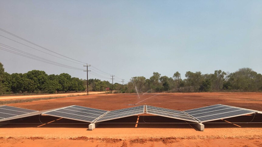 Solar panels sit in triangle shapes surrounded by red dirt