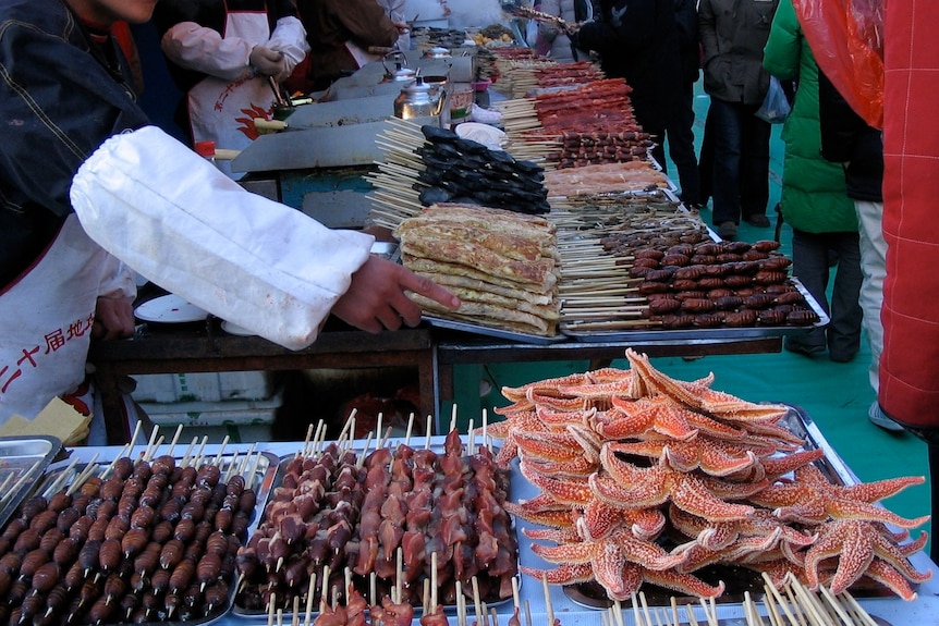 Tables lined with hundreds of different meat and seafood skewers.