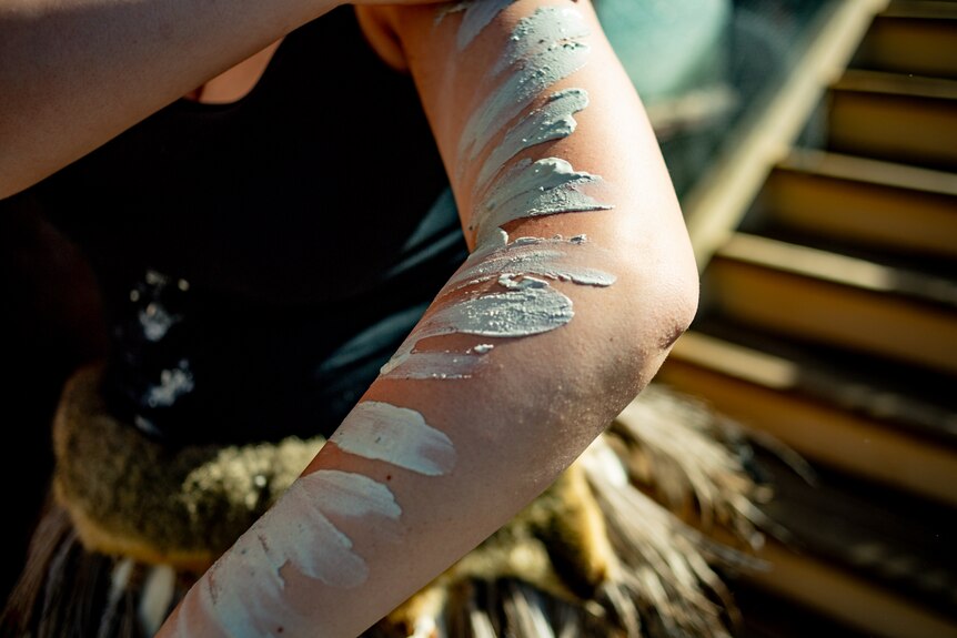 Girl's arm adorned with dashes of thick white body paint 