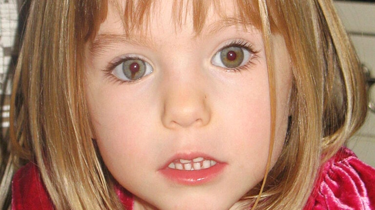 A close up head shot of a young girl with blonde hair and blue eyes.