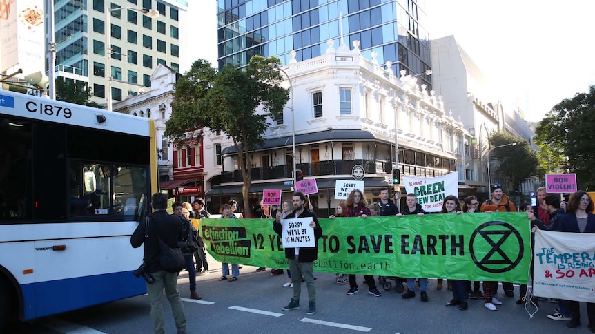 Protesters hold up signs blocking traffic in Brisbane city.