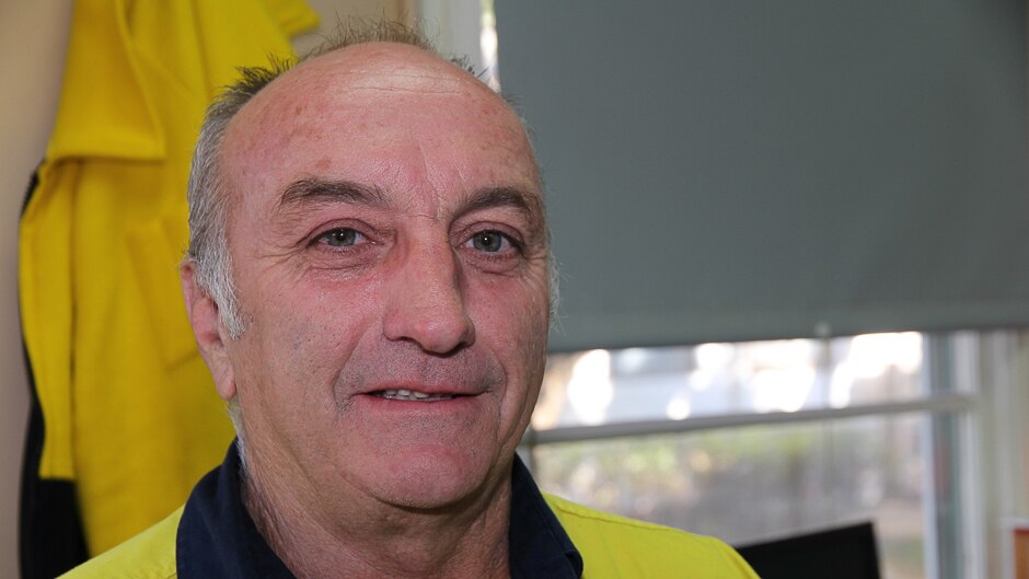 A close up of the face of a man, in high visibility gear in an office