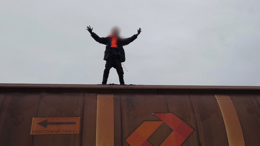 A man stands on a train with his arms in the air