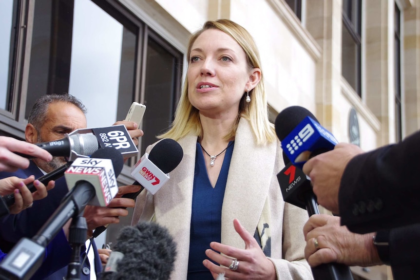 Mia Davies outside State Parliament with media microphones in the foreground.