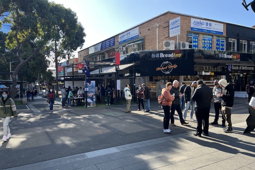 A shopping mall and in the background a public stand with people milling around.